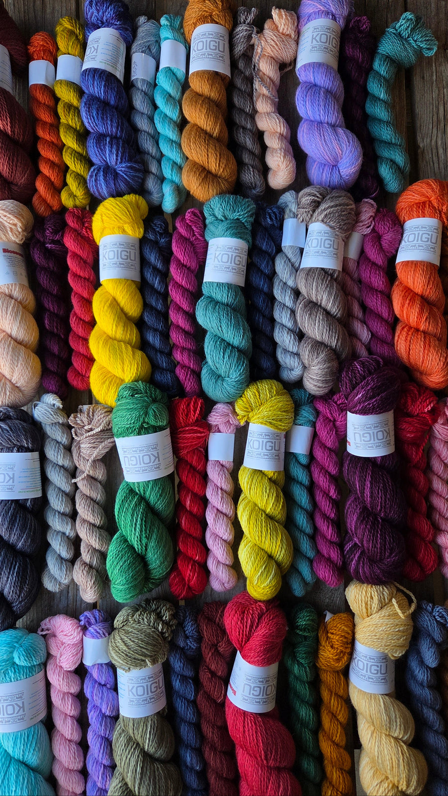 Assorted colorful yarn skeins on a wooden surface
